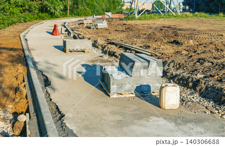 New concrete sidewalk under construction beside cleared earth and construction materials New concrete sidewalk under construction beside cleared earth and construction materials 140306688