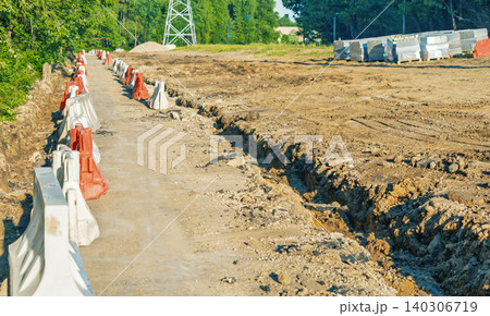Construction site pathway with barriers and earthworks under clear daylight Construction site pathway with barriers and earthworks under clear daylight 140306719