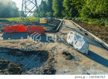 Road construction site with plastic barriers and gravel path in wooded area Road construction site with plastic barriers and gravel path in wooded area 140306767