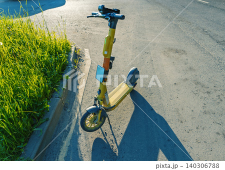 Yellow electric scooter parked at roadside curb in sunlight Yellow electric scooter parked at roadside curb in sunlight 140306788