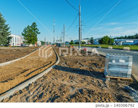 Curved tram rails being installed beside a suburban road on a clear day 140306792