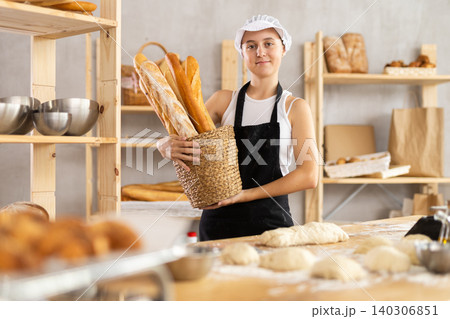 Teen girl holding baguettes in round wicker basket 140306851