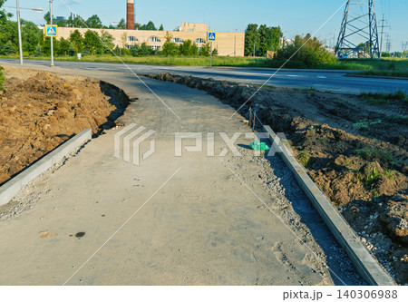 Newly constructed concrete sidewalk along suburban road under bright daylight Newly constructed concrete sidewalk along suburban road under bright daylight 140306988