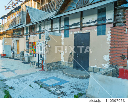 Worn exterior wall and entrance of an old commercial building with tiled courtyard Worn exterior wall and entrance of an old commercial building with tiled courtyard 140307058