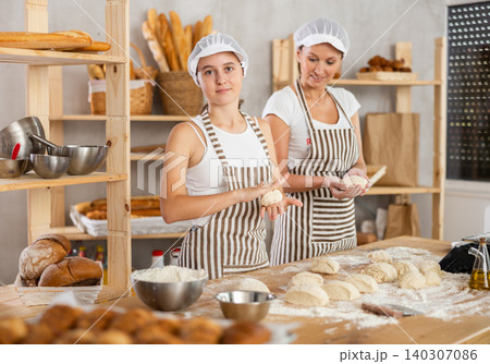 Successful female bakers in apron working in bakery, working with pieces of dough 140307086