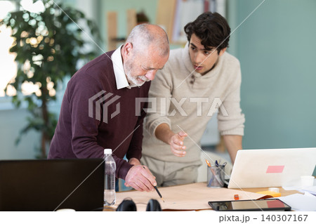 Young and elderly men colleagues discussing building plan in office Young and elderly men colleagues discussing building plan in office 140307167