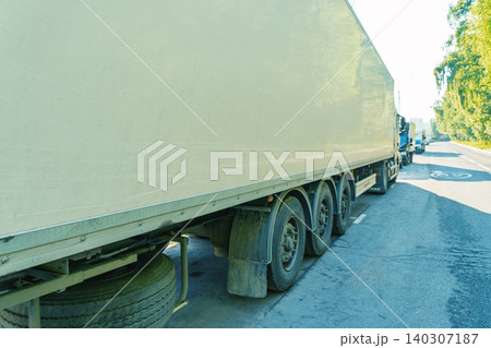 Large white articulated trailer parked on roadside with trucks in queue Large white articulated trailer parked on roadside with trucks in queue 140307187