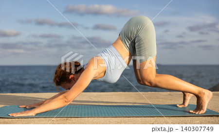 Woman in yoga pose on seashore - dog pose Woman in yoga pose on seashore - dog pose 140307749