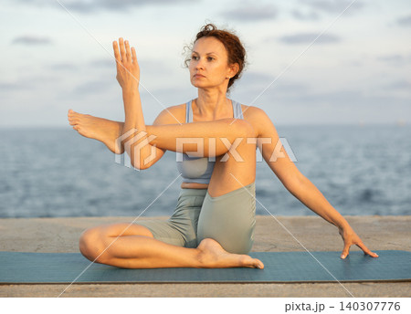 Marchirasana yoga pose on seashore - woman meditating outdoors Marchirasana yoga pose on seashore - woman meditating outdoors 140307776