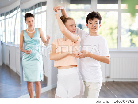 Experienced dance teacher teaching ballroom dancing to a of teenagers in studio 140307862