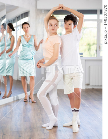 Experienced dance teacher teaching ballroom dancing to a of teenagers in studio Experienced dance teacher teaching ballroom dancing to a of teenagers in studio 140307870