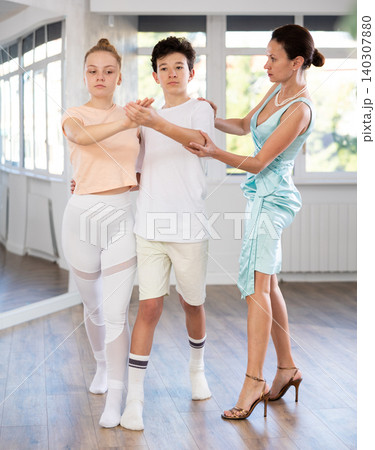 Dance lesson - teacher teaches teenage girl and boy to dance tango in studio 140307880