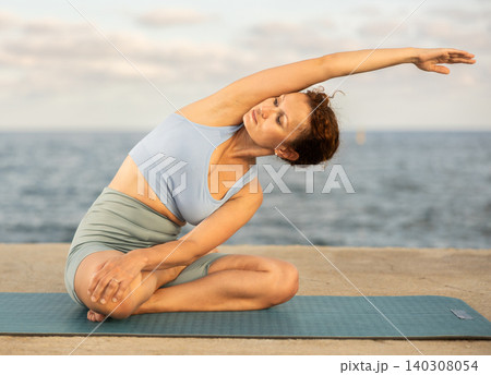 Yoga practice on embankment, female athlete fulfil carry out padmasana svastikasana, Siddhasana 140308054