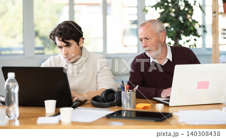 Elderly and young men working in office 140308438