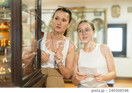 Young woman with teen daughter walk around museum, cookware zone. 140308596