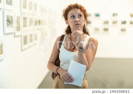 Woman observing photographs on display in photo gallery Woman observing photographs on display in photo gallery 140308681