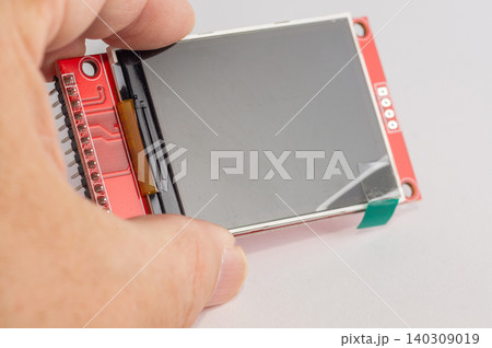 Close-up of an OLED display for microcontroller devices held in a hand. 140309019