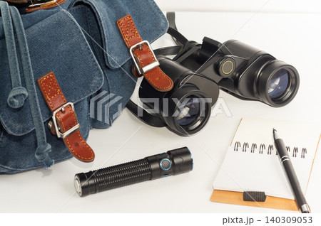 Backpack, binoculars, flashlight, and notebook in close-up against a white background. Backpack, binoculars, flashlight, and notebook in close-up against a white background. 140309053