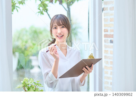 ペンを手に明るく笑顔を見せる女性 ペンを手に明るく笑顔を見せる女性 140309902