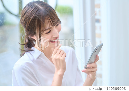 スマホを見ながら考える女性 140309908