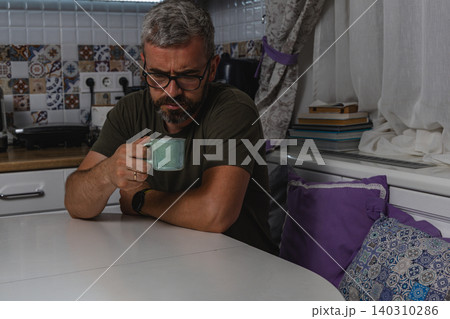 Man enjoys morning coffee during a quiet moment at home Man enjoys morning coffee during a quiet moment at home 140310286