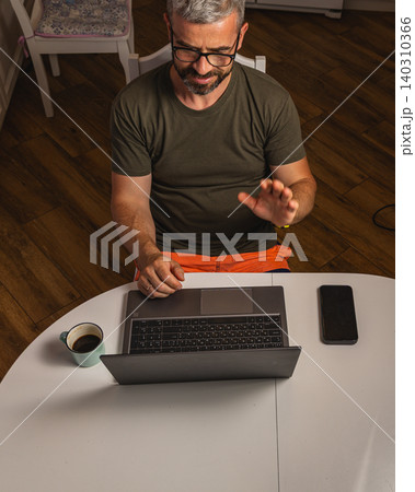 Man enjoys coffee while working on laptop at home in the morning Man enjoys coffee while working on laptop at home in the morning 140310366