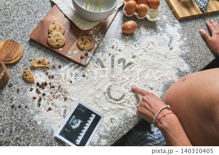 Pregnant woman baking cookies with ultrasound and flour Pregnant woman baking cookies with ultrasound and flour 140310405