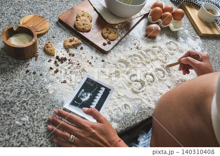 Pregnant woman baking cookies announcing baby coming soon Pregnant woman baking cookies announcing baby coming soon 140310408