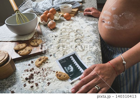 Pregnant woman baking cookies, announcing baby coming soon Pregnant woman baking cookies, announcing baby coming soon 140310413