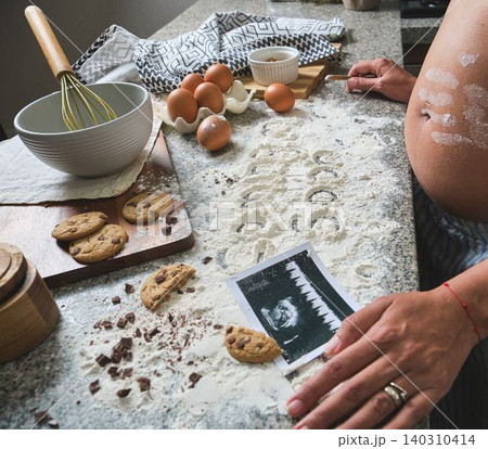 Pregnant woman baking cookies with ultrasound image Pregnant woman baking cookies with ultrasound image 140310414
