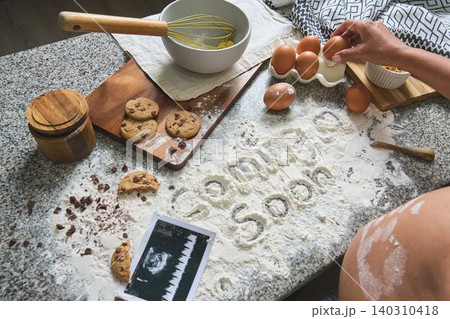 Pregnant woman baking cookies for baby announcement Pregnant woman baking cookies for baby announcement 140310418