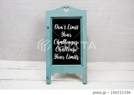 Don't Limit Your Challenges, Challenge Your Limits text written on wooden blue easel Don't Limit Your Challenges, Challenge Your Limits text written on wooden blue easel 140311336