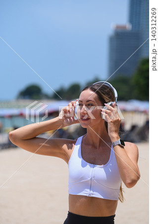 Healthy lifestyle concept: Happy woman listening to music on the sunny beach Healthy lifestyle concept: Happy woman listening to music on the sunny beach 140312269
