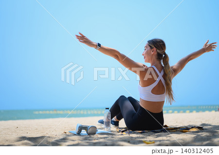 Young woman sitting on the sand with open arms enjoying summer vacation and freedom Young woman sitting on the sand with open arms enjoying summer vacation and freedom 140312405