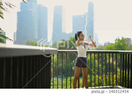 Runner woman stretching warmup on skywalk in park with urban city Runner woman stretching warmup on skywalk in park with urban city 140312454