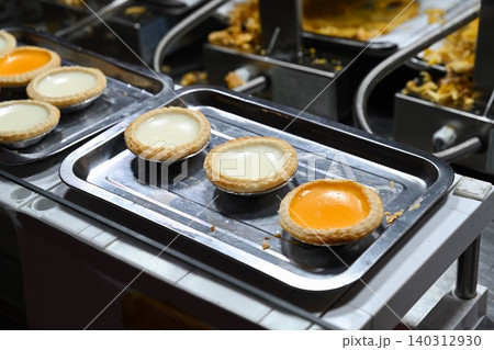 Traditional hong kong egg tarts and milk tarts on metal trays at Temple Street Night Market street food stall under lights in Hong Kong Traditional hong kong egg tarts and milk tarts on metal trays at Temple Street Night Market street food stall under lights in Hong Kong 140312930