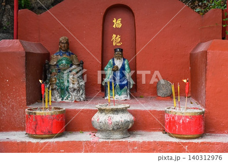 Traditional Chinese shrines of Tu Di Gong Earth God with burning incense sticks in bowls at red outdoor altar in Macau 140312976