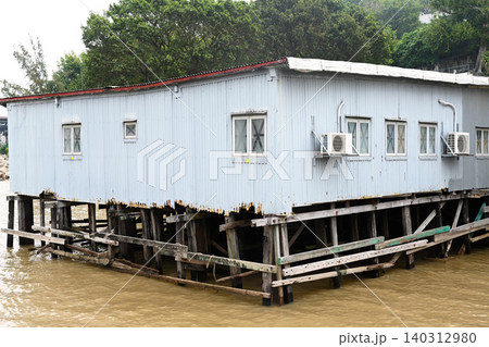 Traditional stilt house made of corrugated metal sheets on wooden pillars over water at historic Coloane Village in Macau Traditional stilt house made of corrugated metal sheets on wooden pillars over water at historic Coloane Village in Macau 140312980