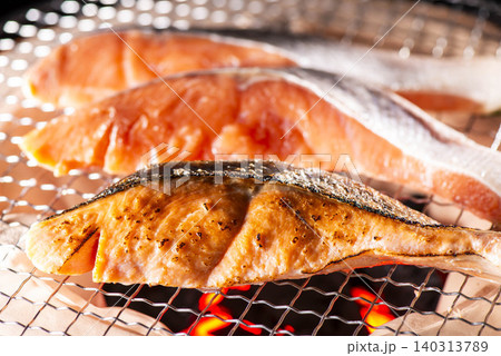 炭火で焼いた鮭が網の上で香ばしく仕上がる、新鮮な食材の和風焼き魚 炭火で焼いた鮭が網の上で香ばしく仕上がる、新鮮な食材の和風焼き魚 140313789