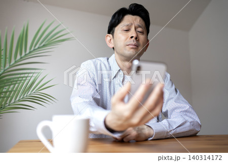 老眼でスマホの画面が見にくいミドル男性 老眼でスマホの画面が見にくいミドル男性 140314172