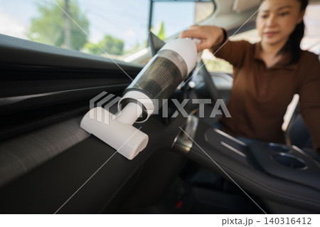 woman using portable handheld vacuum cleaner to clean dust on an electric car dashboard woman using portable handheld vacuum cleaner to clean dust on an electric car dashboard 140316412