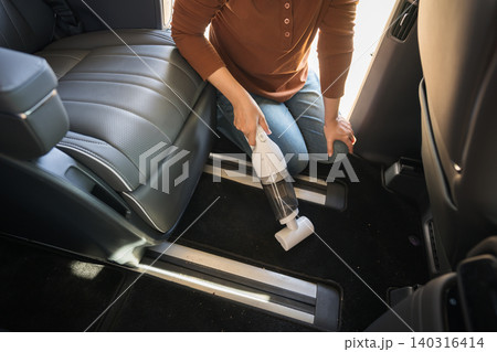 close up hand of woman using portable handheld vacuum cleaner to cleaning the floor mat of her luxury car close up hand of woman using portable handheld vacuum cleaner to cleaning the floor mat of her luxury car 140316414