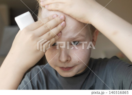 Cute 10 years old boy applying mineral sunscreen stick on his face. Caucasian child protecting freckled skin from sun damage with spf stick at home. 140316865