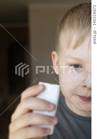 Cute 10 years old boy applying mineral sunscreen stick on his face. Caucasian child protecting freckled skin from sun damage with spf stick at home. Cute 10 years old boy applying mineral sunscreen stick on his face. Caucasian child protecting freckled skin from sun damage with spf stick at home. 140316872