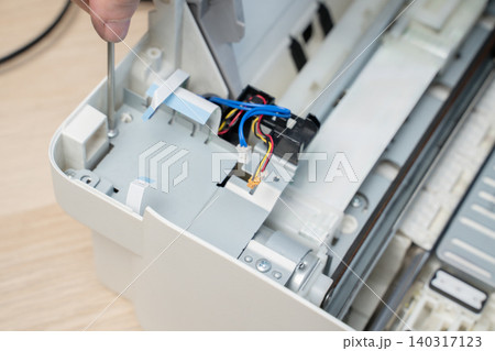 Hand Using Screwdriver Repairing Inkjet Printer Interior With Exposed Wires And Cables Hand Using Screwdriver Repairing Inkjet Printer Interior With Exposed Wires And Cables 140317123
