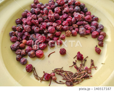 Spoiled phalsa berries on yellow plate beside separated fruit stems Spoiled phalsa berries on yellow plate beside separated fruit stems 140317187