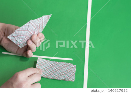 Hands dealing playing cards on green casino table with white lines. 140317932