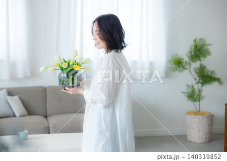 リビングで花瓶を持つ若い女性　 140319852