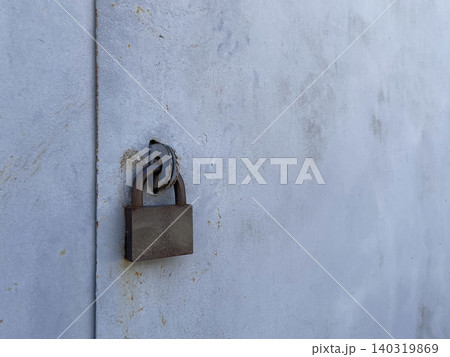 Rusty Padlock Securing Weathered Metal Garage Door With Peeling Paint Texture 140319869