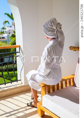 A Russian female tourist enjoys the bright warm sun on a hotel balcony during a relaxing holiday 140321796